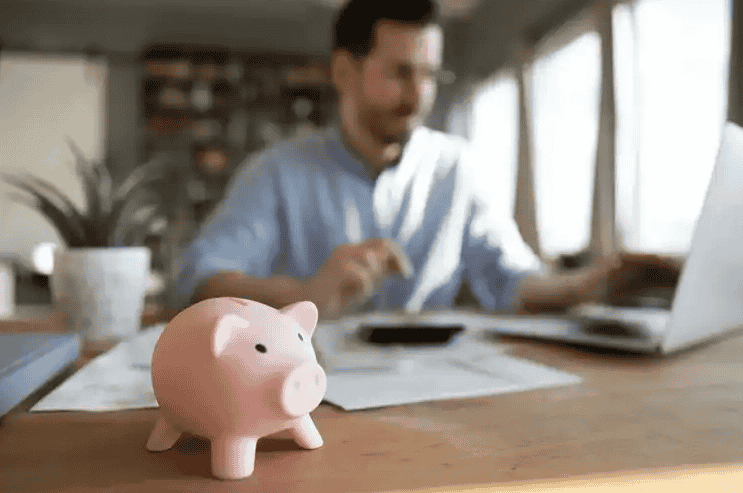 Man at a laptop with a piggy bank